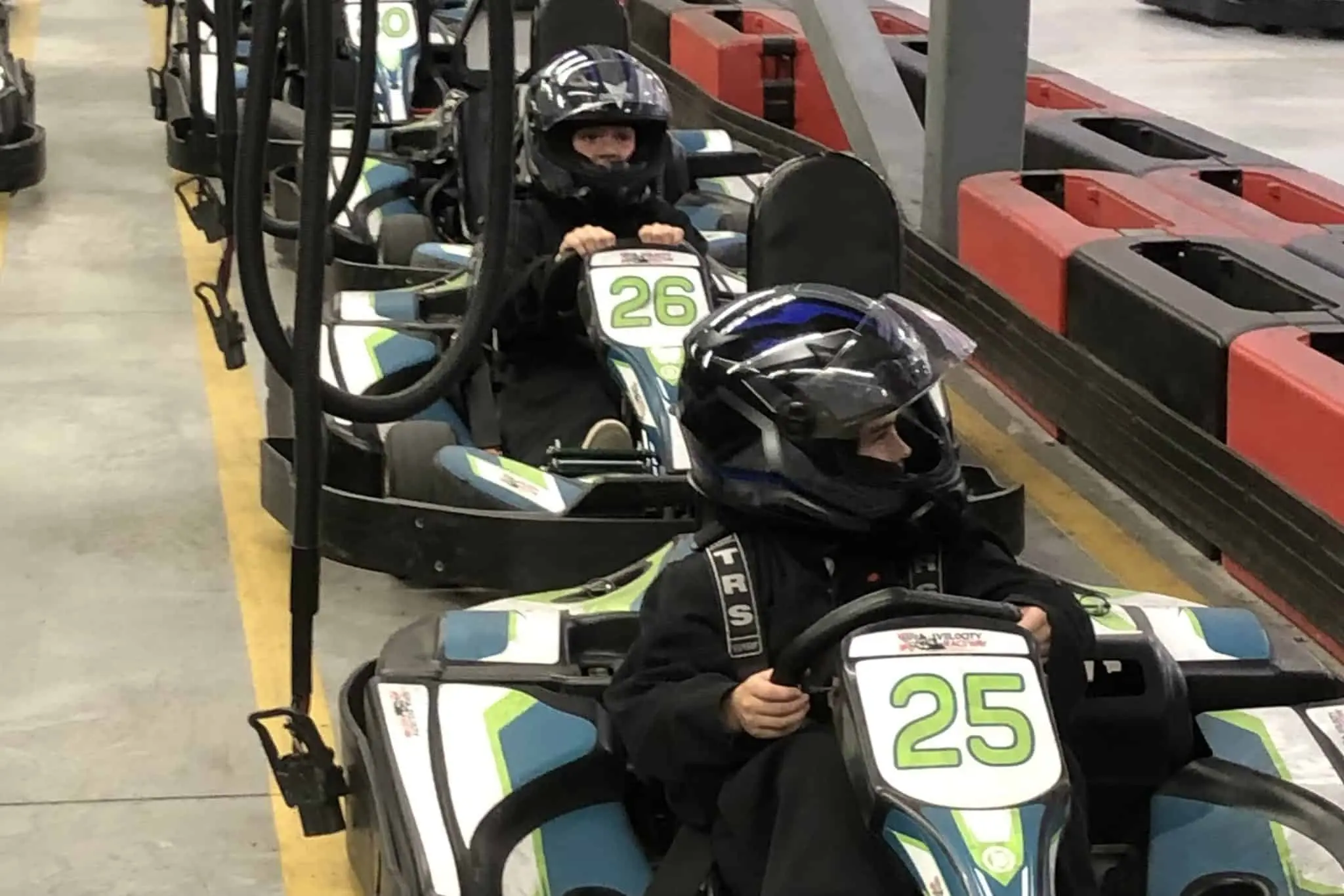 Kids wearing helmets racing go karts at the Stoked Centre indoor track in Saskatoon.
