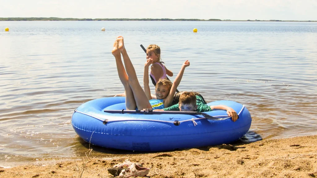 Saskatoon Day Trips Children playing in an inflatable raft along the sandy beach at Douglas Provincial Park.