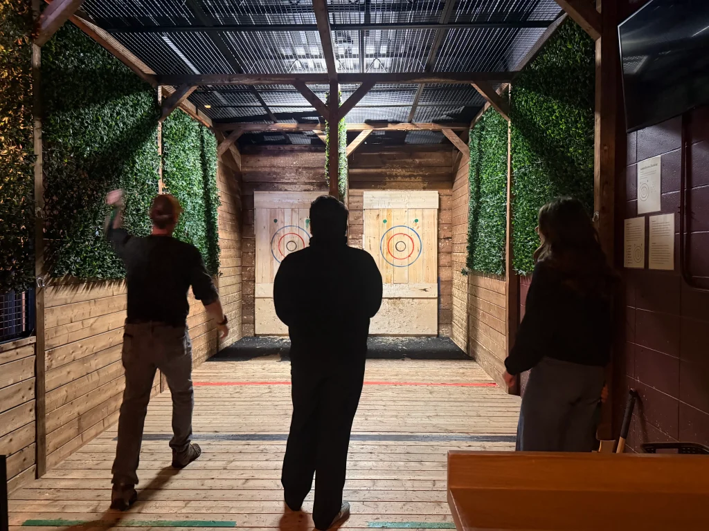 a man getting ready to throw an axe at the target with others standing nearby watching