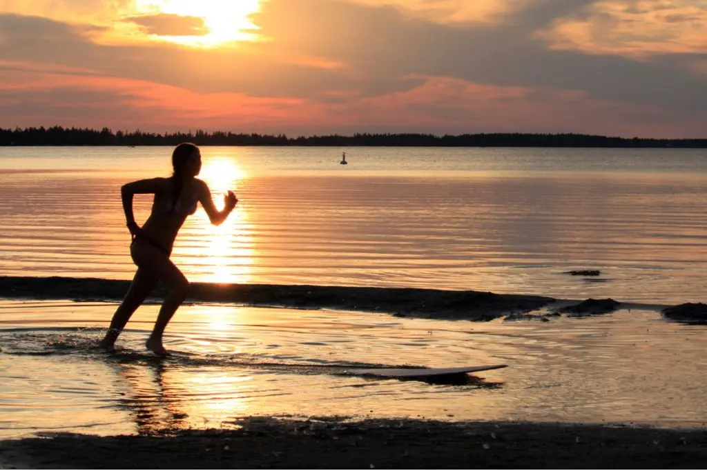 Silhouette of a person running through shallow water at sunset on Candle Lake in northern Saskatchewan.