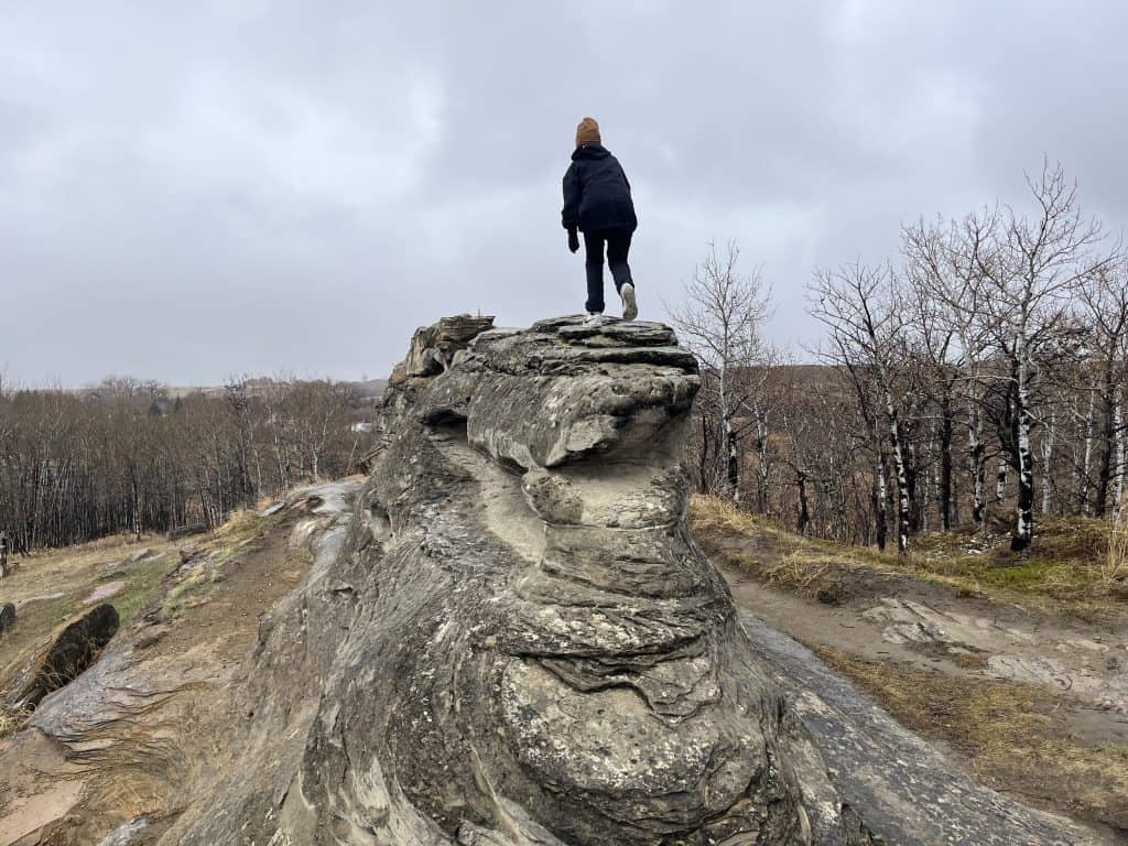 Roche Percee Sarah walking away on top of a large unique rock formation