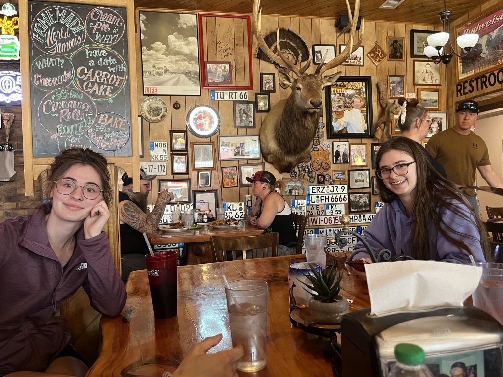 Jaimie and Emma sitting at the table inside Westside Lilo's with memorabilia on the walls in the background.