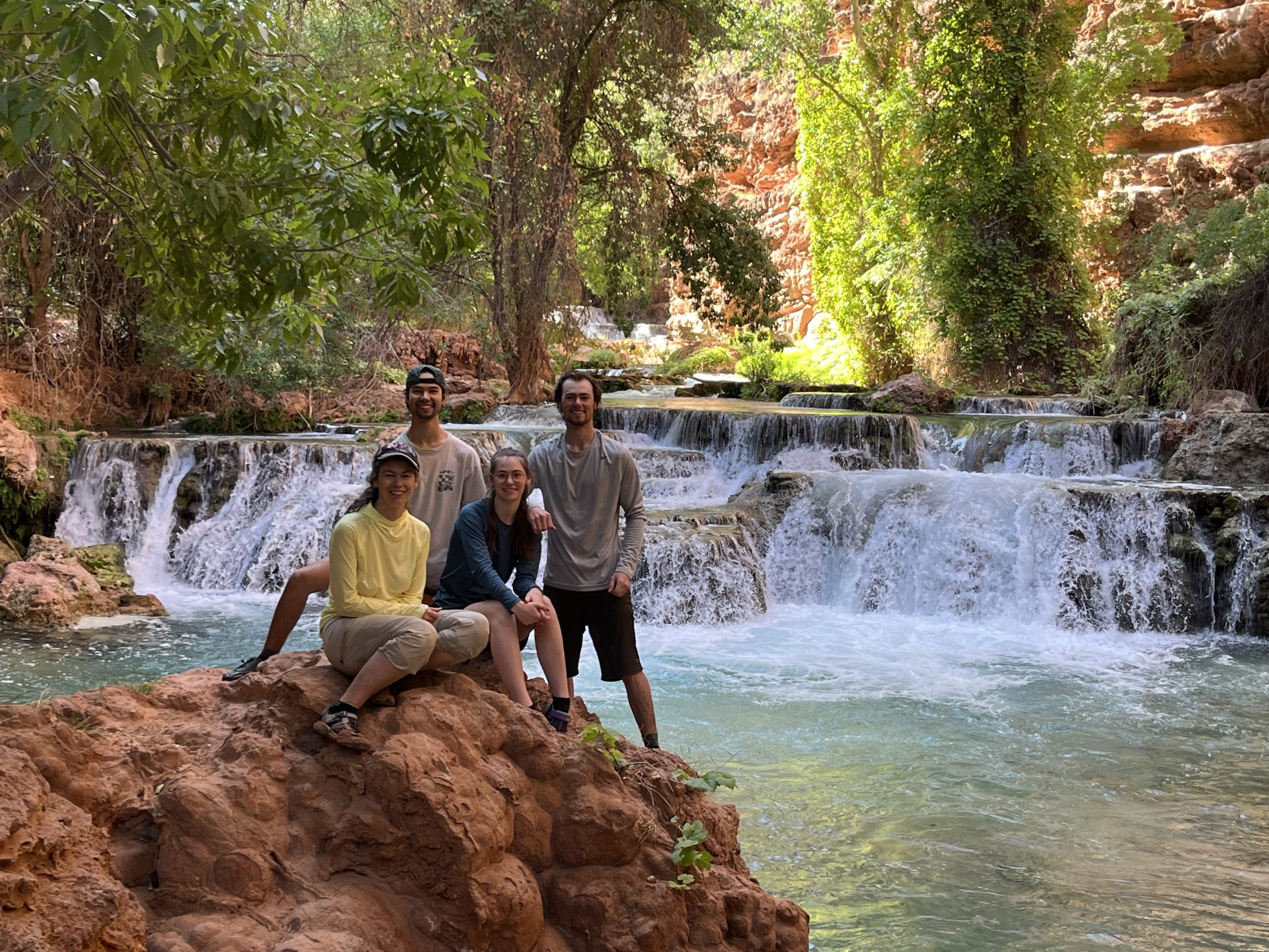 Hikers resting beside a small travertine waterfall along the Beaver Falls trail.