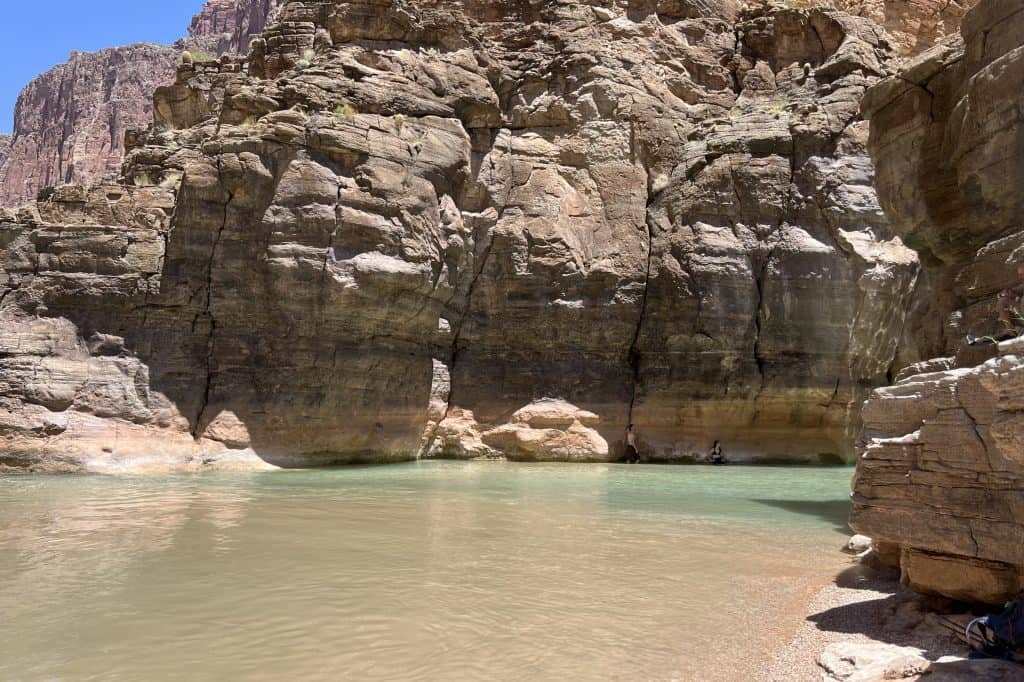 Havasupai Confluence Joshua and Jaimie standing in the Havasu Creek near the junction of the two rivers with the canyon walls towering above them.