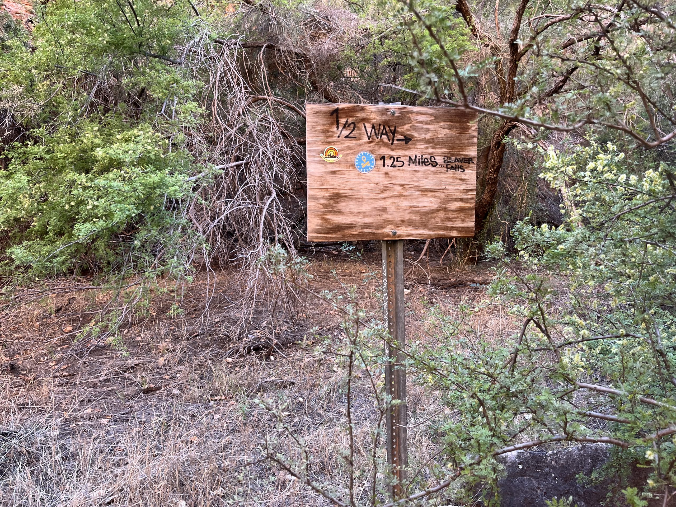 Wooden sign indicating the halfway point to Beaver Falls along the trail.
