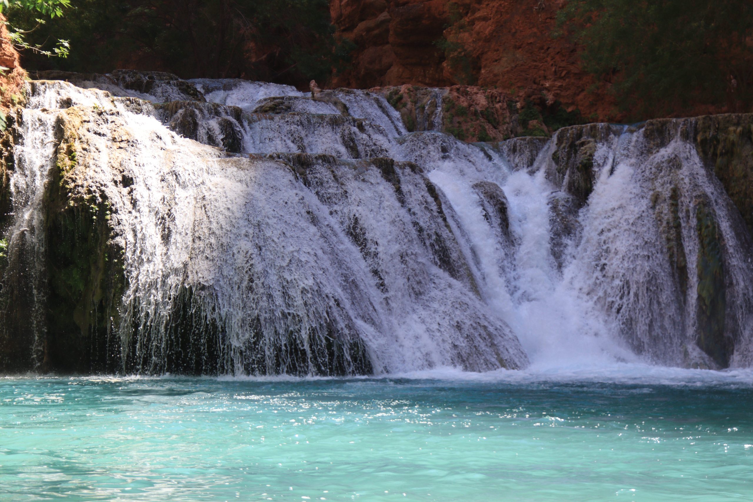 Wide cascade at Beaver Falls spilling over travertine ledges into a turquoise pool in Havasupai Canyon.