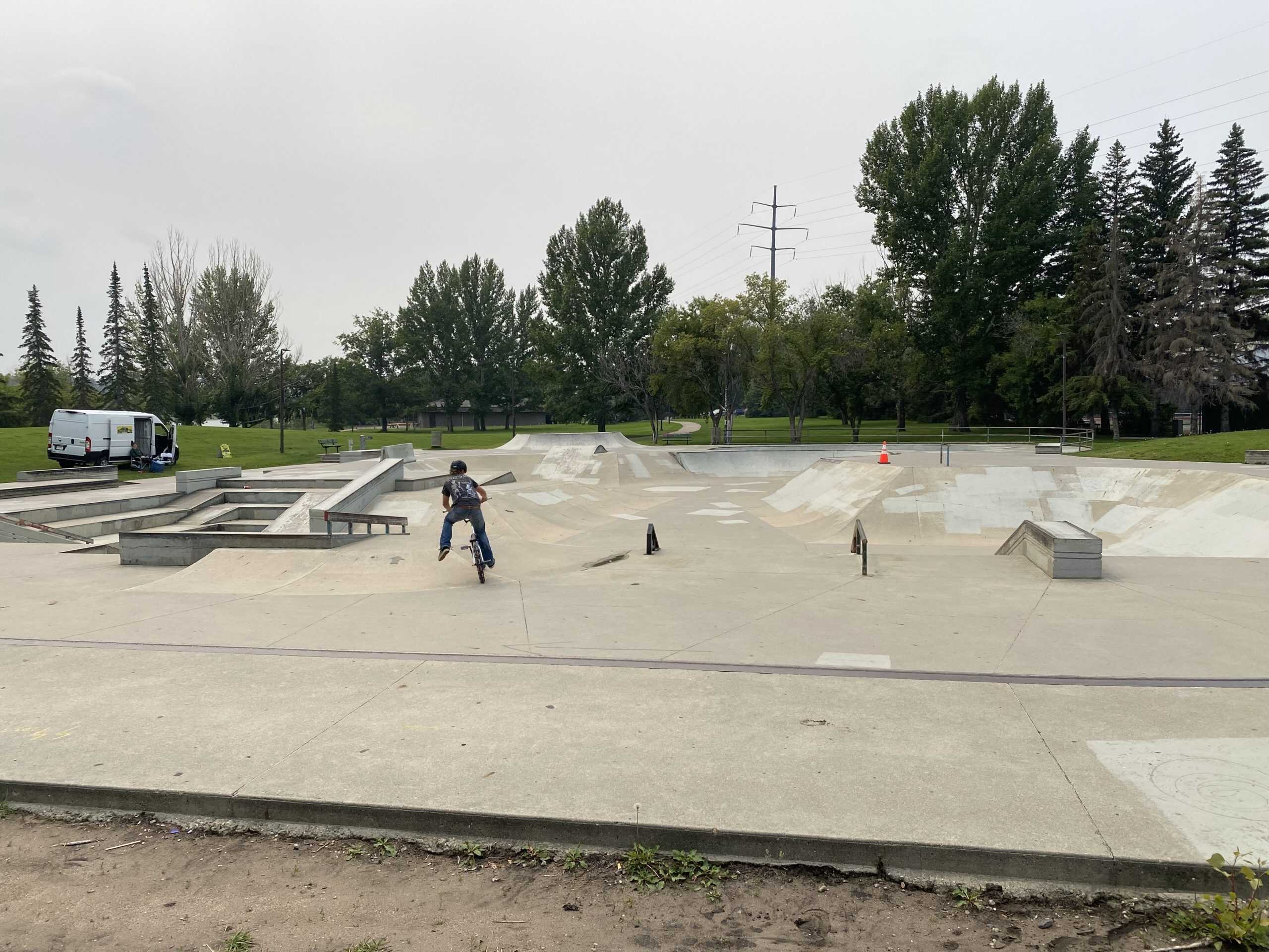Skate park at Victoria Park in Saskatoon with a rider using the concrete ramps and bowls.