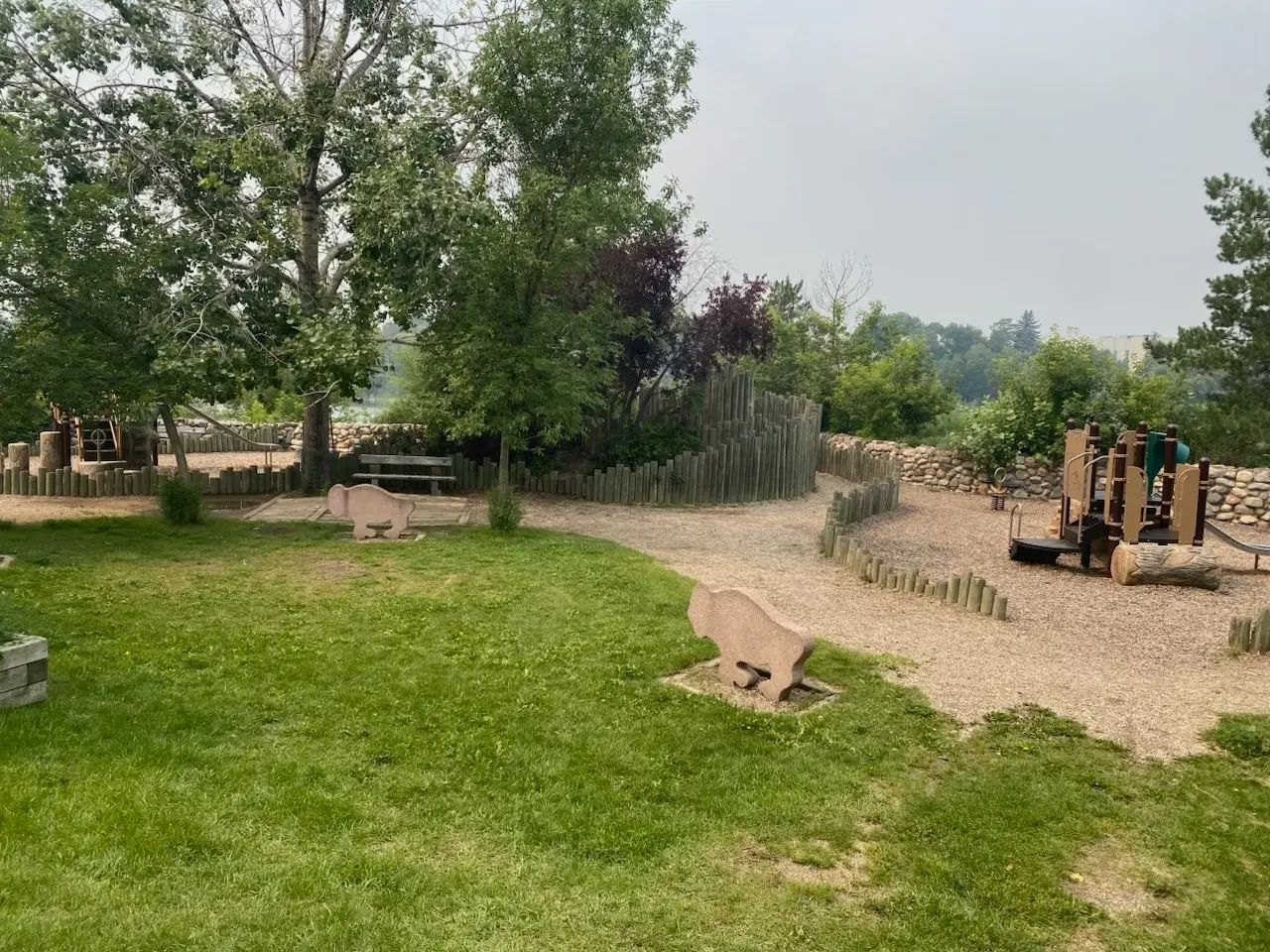 Playground area at Gabriel Dumont Park along the Meewasin Trail in Saskatoon, with grassy space and wooden play structures.