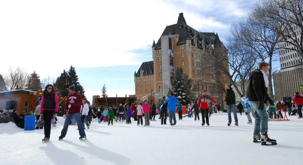 free things to do in Saskatoon several people skating on Saskatoon's free Cameco Meewasin Skating Rink beside the bessberough Hotel on a sunny winter day.