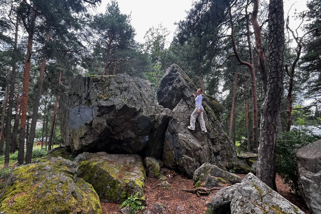 Sarah standing on the large boulders in the forest beside Iso Linnamäki