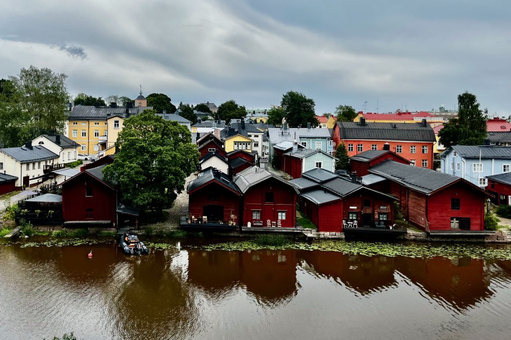 View of Old Porvoo colourful houses, red warehouses, and river from trail leading to Iso Linnamäki