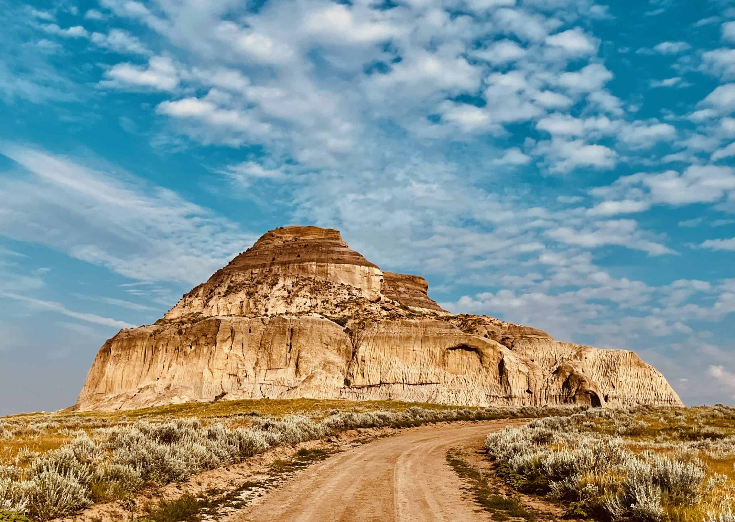 Castle Butte rising above the prairie in the Big Muddy Badlands of southern Saskatchewan, with a dirt road leading toward the formation.