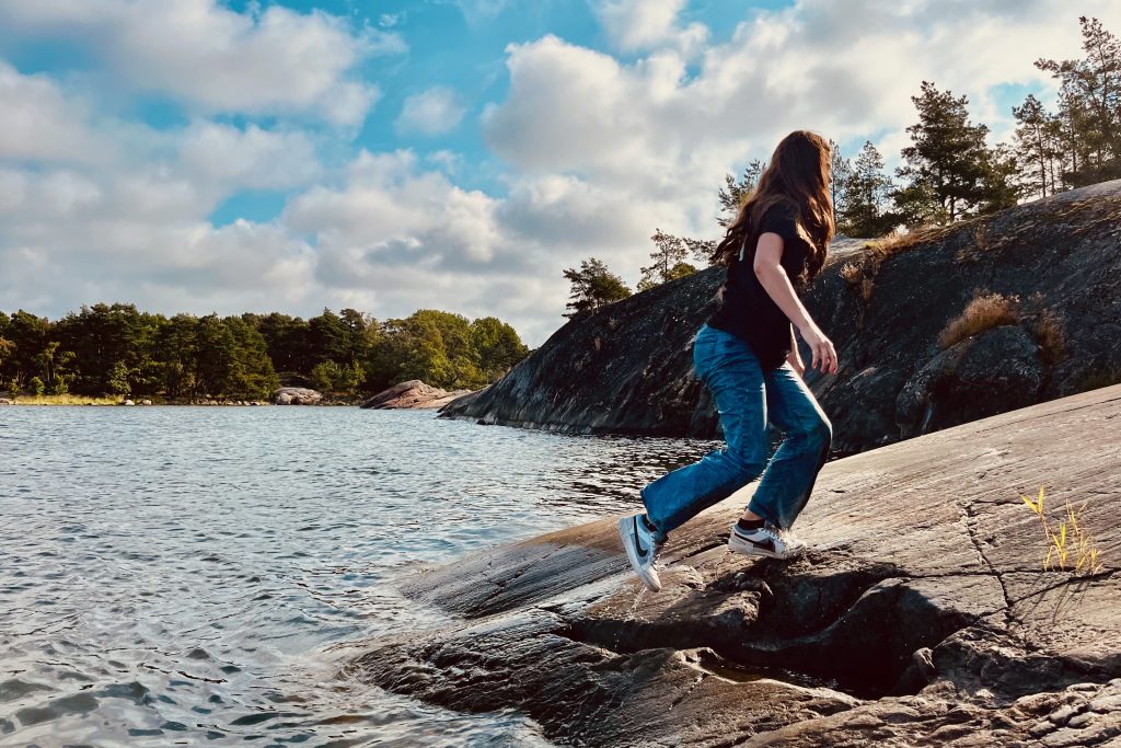Granite cliffs along the Baltic coast with Sarah walking out of the Baltic Sea, up the cliff.