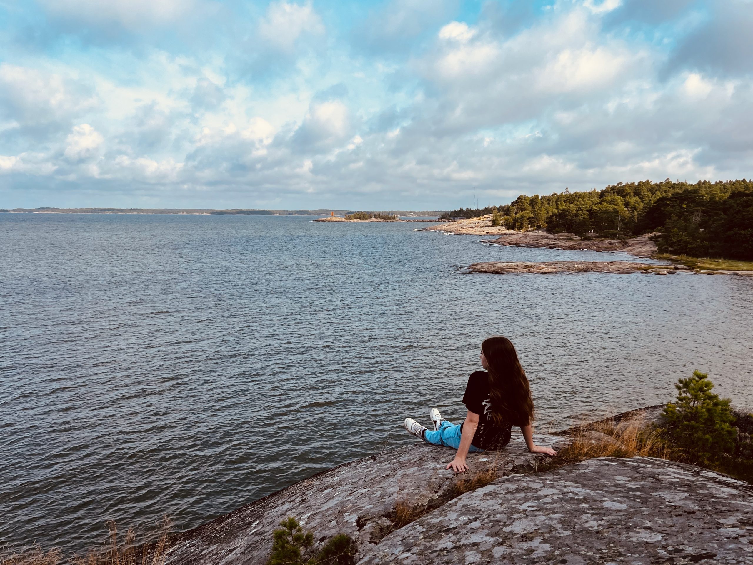Sarah sitting on a slab of granite on the Porkkalanniemi shore, looking out over the Baltic Sea.