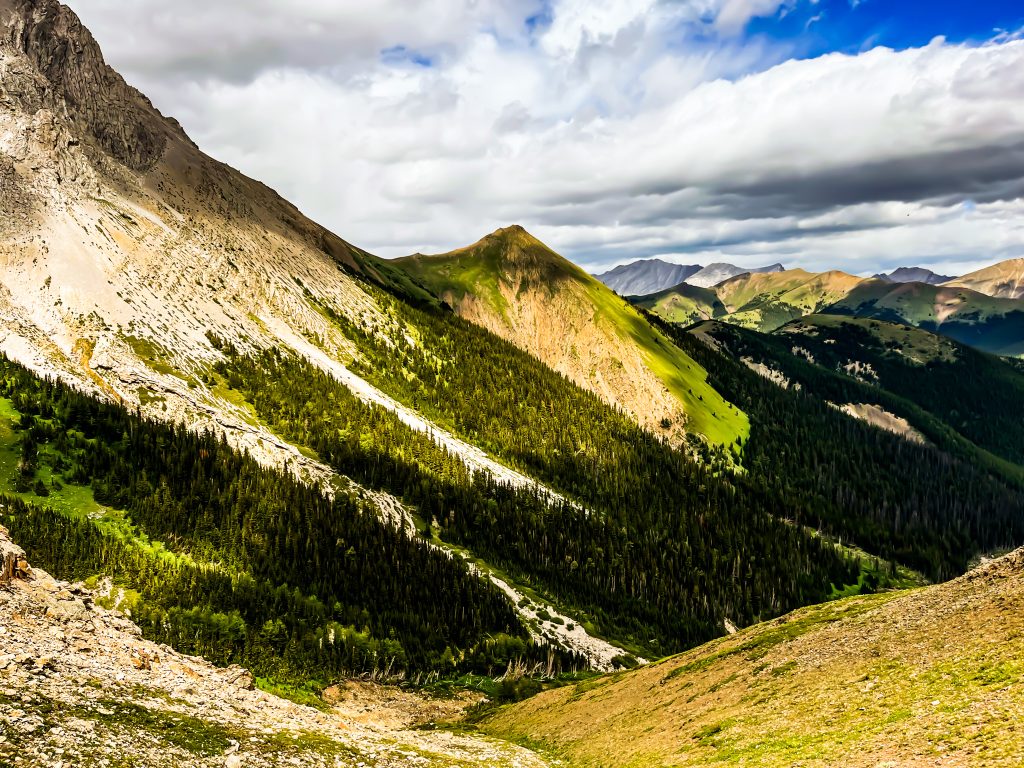 off the beaten path Kananaskis hikes View of the valley from the trail on Mist Mountain. Blue sky with white clouds and mountains in the background.