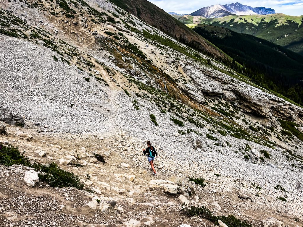 off the beaten path Kananaskis hikes a lone hiker on a ridge of loose rocks.Mountains in the background and the trail stretching ahead.