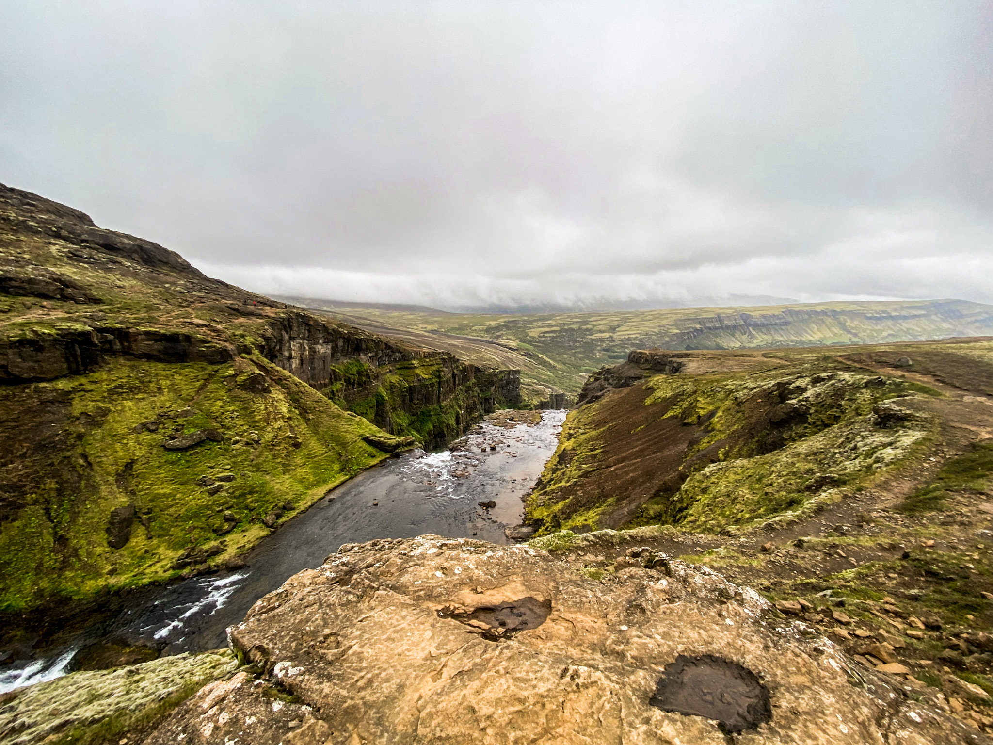 A wide moss-covered canyon with a river flowing through it, photographed from a high point on the Glymur trail well past the main waterfall viewpoint.