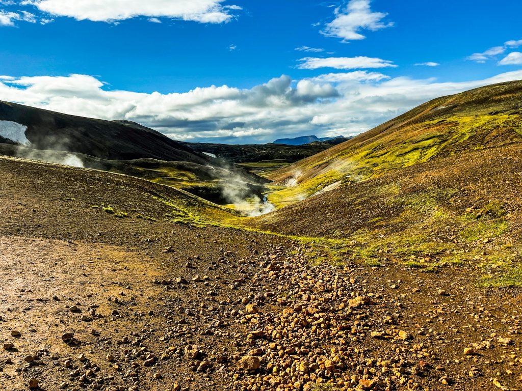 Laugavegur and Fimmvörðuháls combo Steaming vents surrounded by rhyolite mountains with bright blue sky and puffy clouds