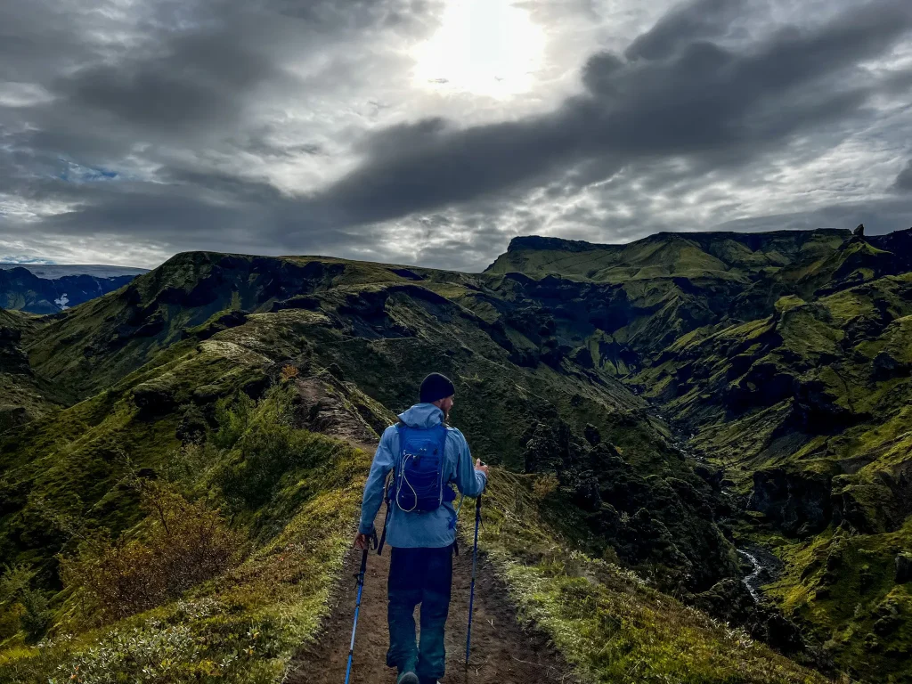 Hiker walking along the exposed Fimmvörðuháls ridge under darkening storm clouds