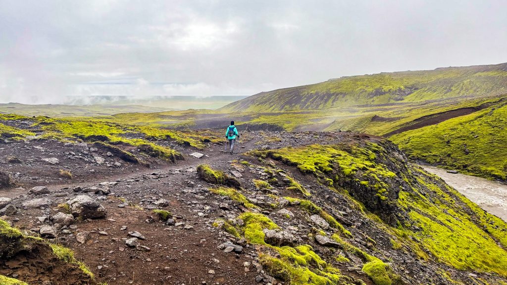 Hiker walking along the trail above the river with moss covered hills all around