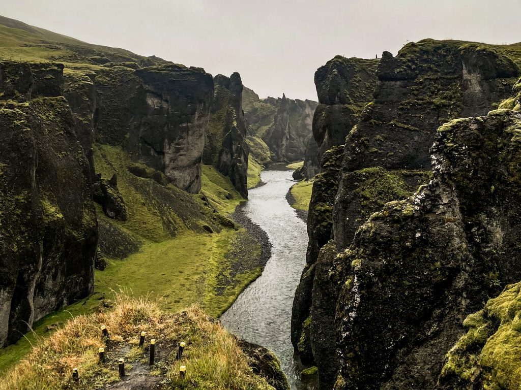 Moss-covered cliffs rising above a narrow river winding through Fjaðrárgljúfur canyon in southern Iceland.