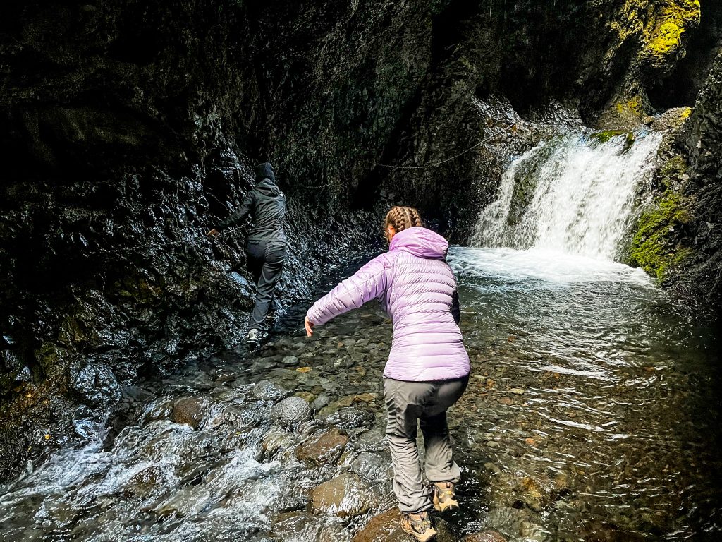 hikers navigating the river crossing in Nauthúsagil Ravine