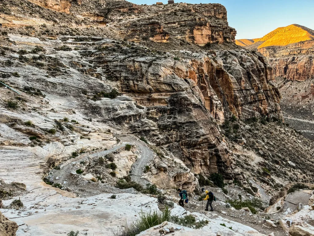 Two hikers following the hardest part of the Havasupai trail down the switchbacks into the canyon