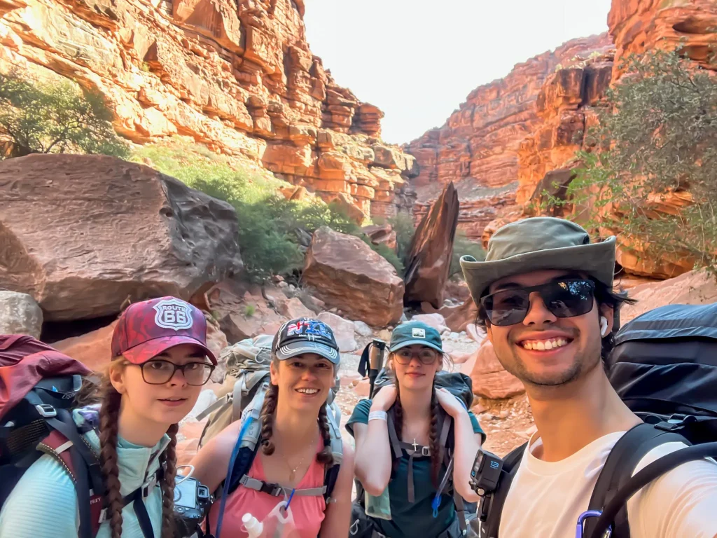 Four hikers take a selfie on the Havsupai Trail with canyon walls beside and behind them.
