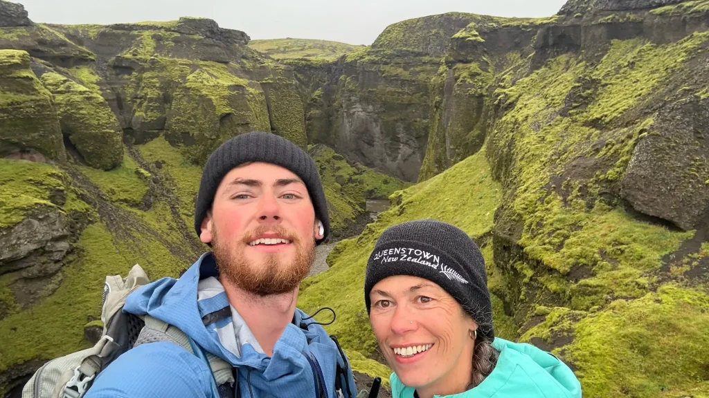 Two hikers on the Fimmvörðuháls extension after the first steep climb, overlooking a moss-covered canyon in Iceland