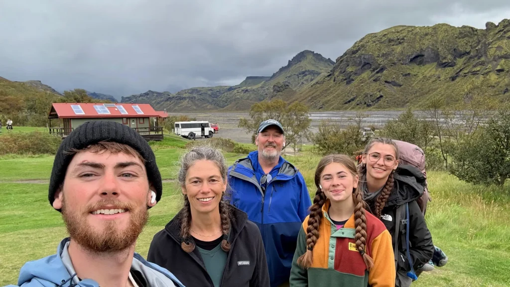 Group of hikers standing at Langidalur camp in Þórsmörk, with green valley slopes and mountains in the background