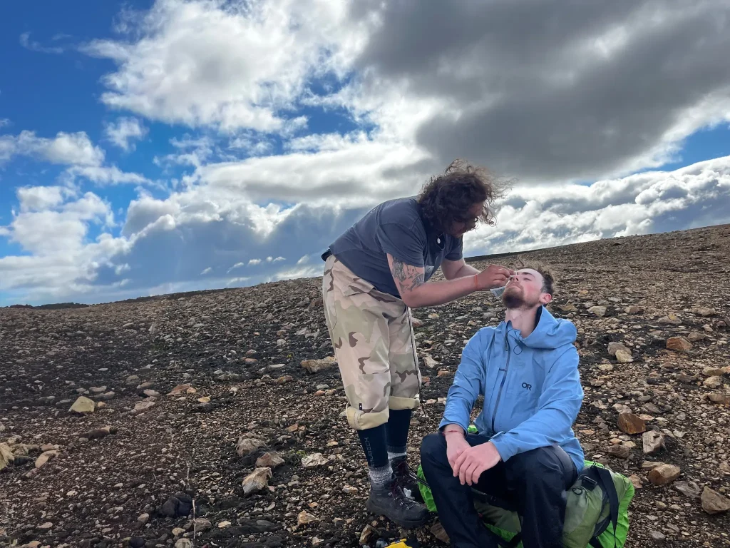 A hiker giving first aid to another hiker on the trail between Landmannalaugar and Hrafntinnusker 