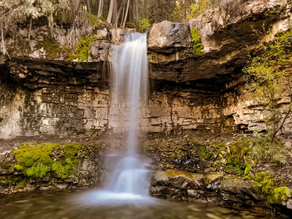 Troll Falls dropping over a rocky cliff surrounded by moss and fores