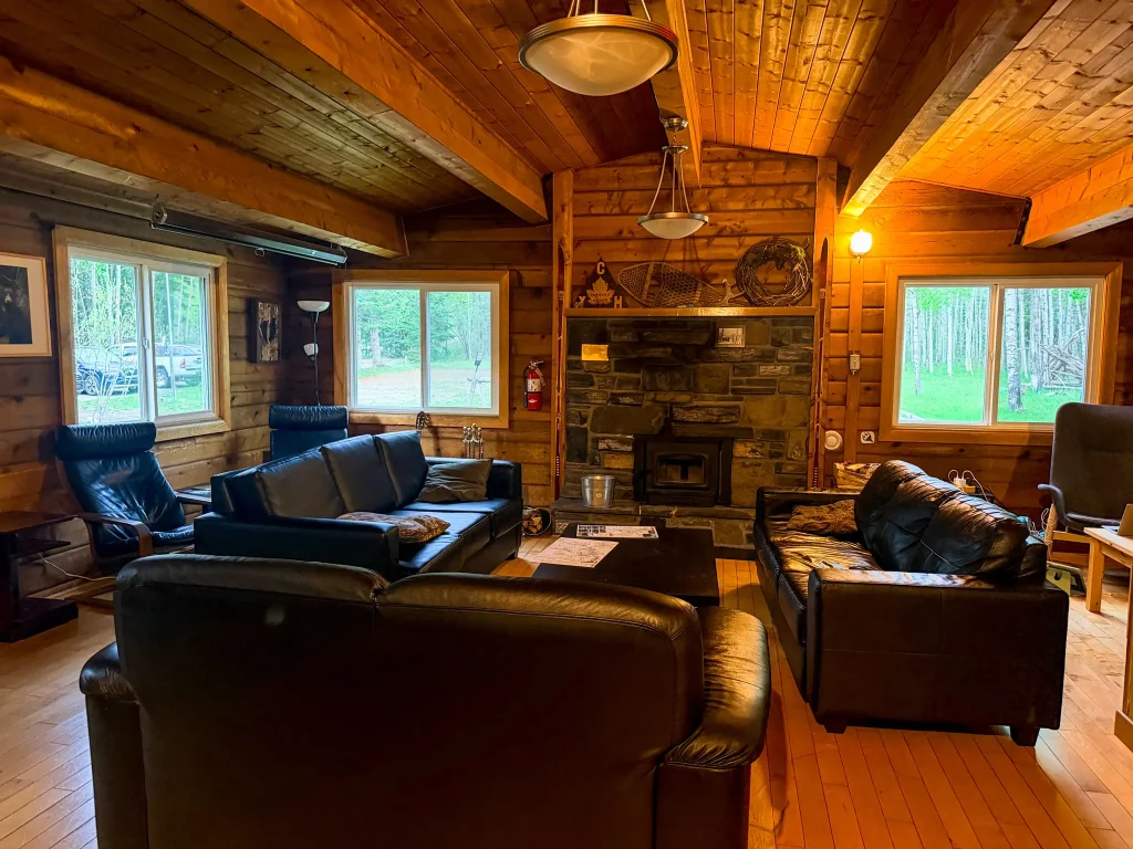 Wood-paneled common room with leather couches and fireplace at HI Kananaskis Wilderness Hostel